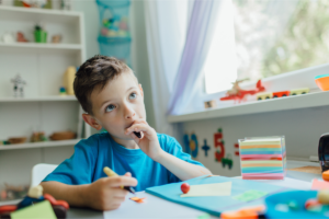 boy concentrating at desk while chewing a pen