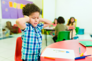 Child with autism touching ears showing sensory self-regulation behavior